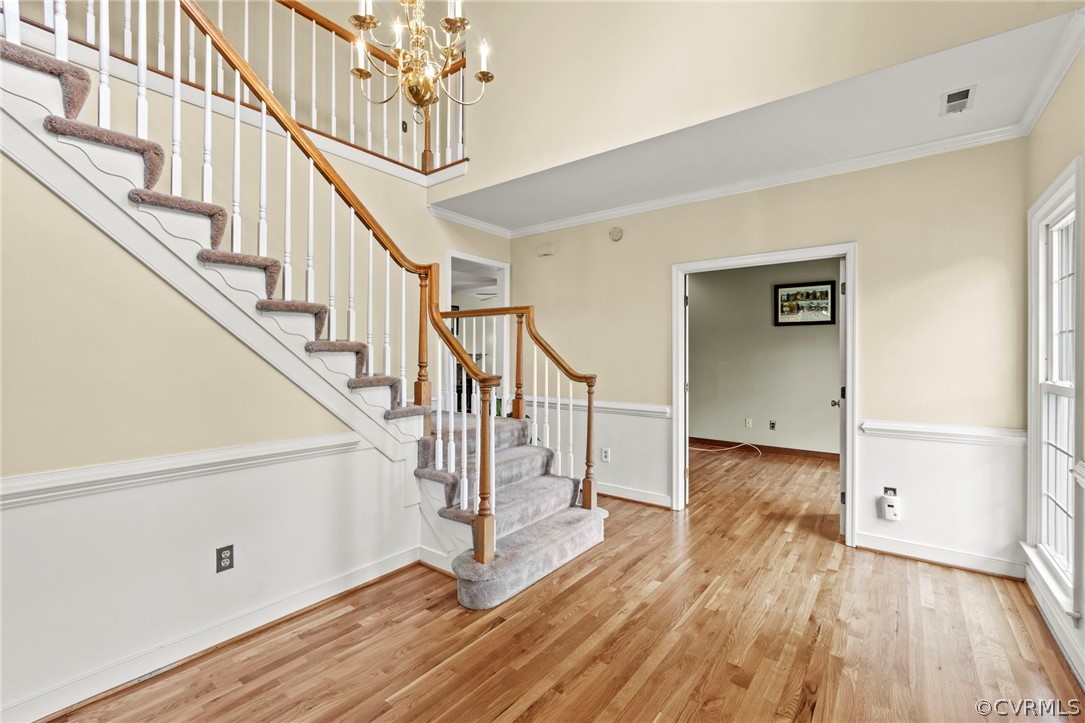 Foyer entrance featuring a chandelier, ornamental molding, and light hardwood / wood floors