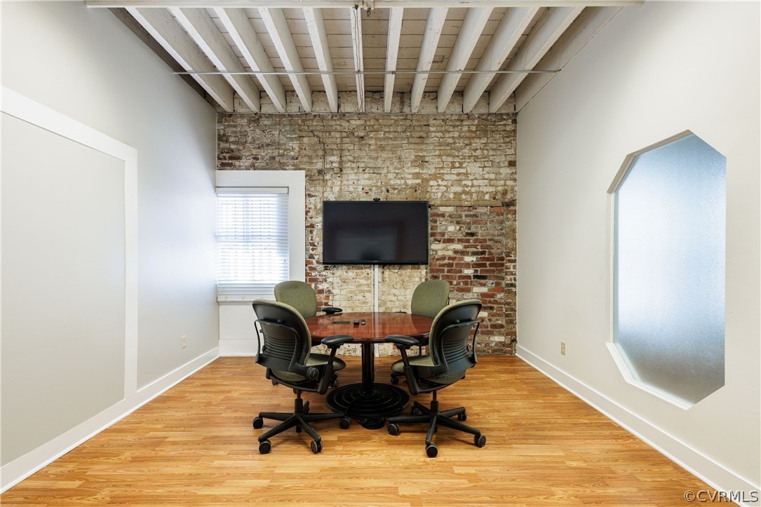 Office area with beam ceiling and light hardwood / wood-style floors