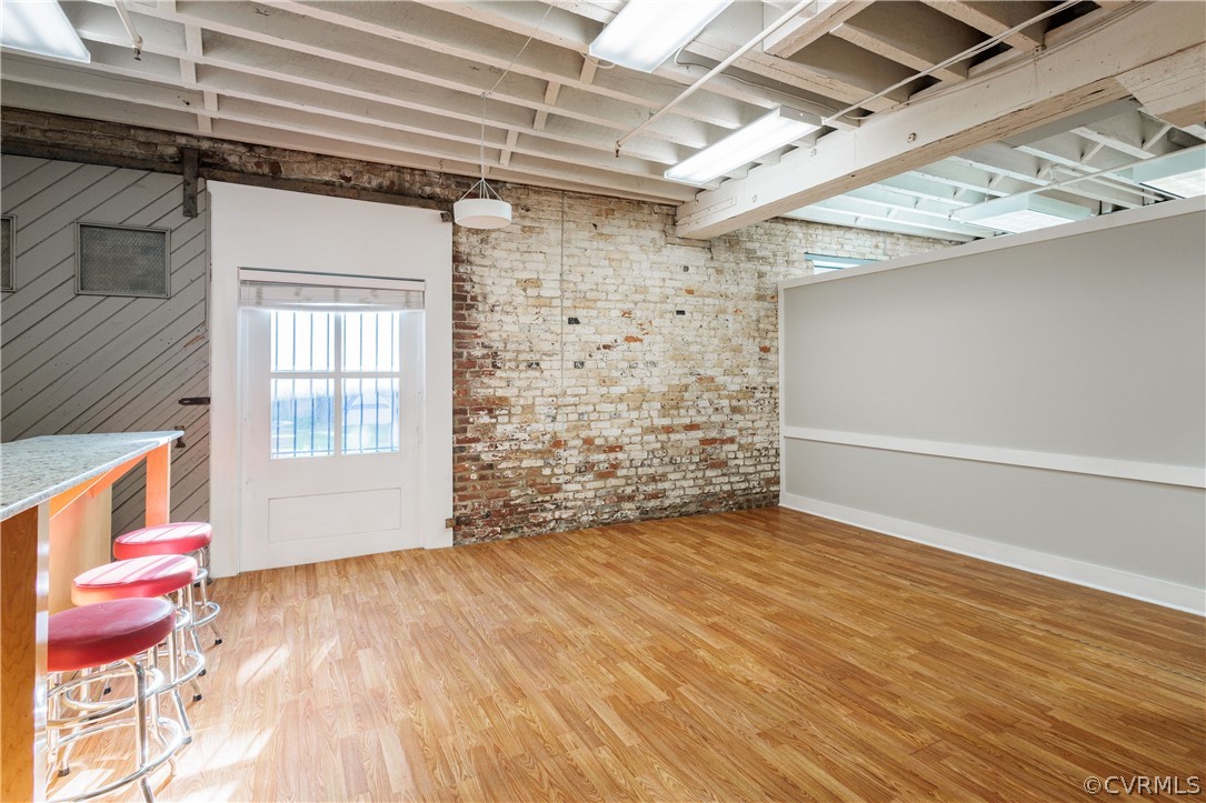Empty room with brick wall, light wood-type flooring, and a barn door
