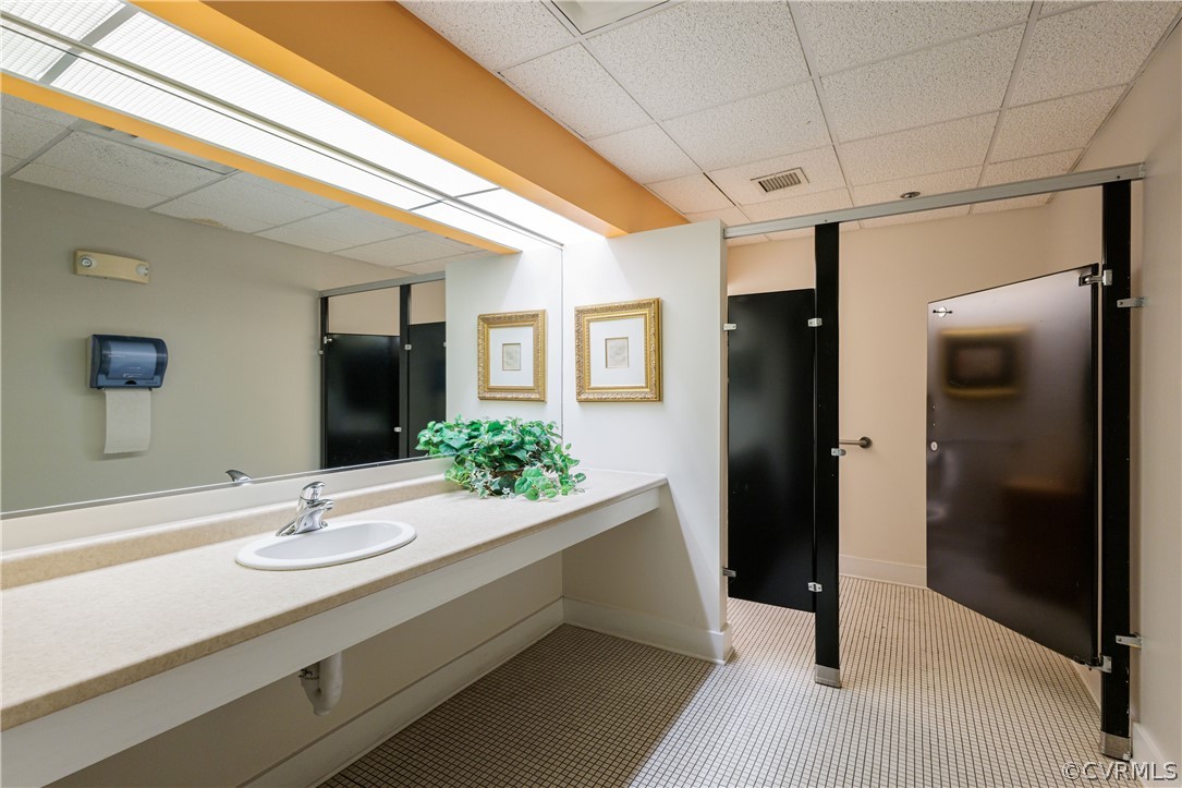 Bathroom featuring a drop ceiling, tile floors, and vanity