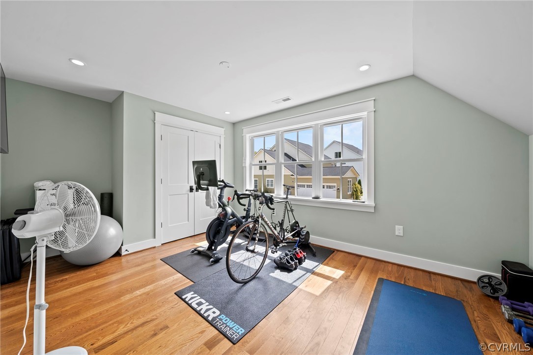 Workout room featuring light hardwood / wood-style flooring and vaulted ceiling