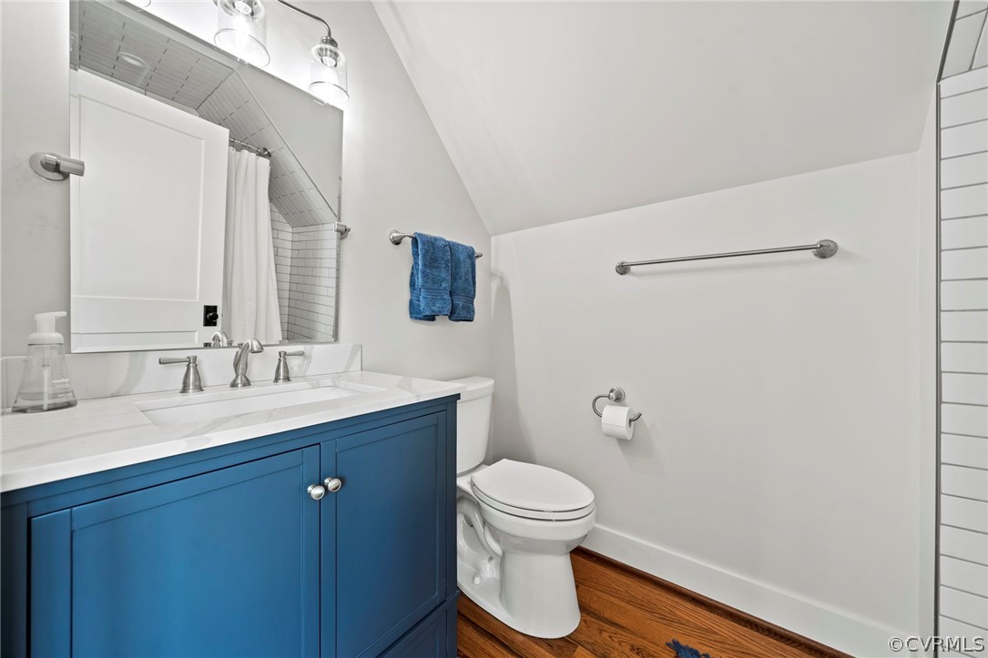 Bathroom with hardwood / wood-style flooring, lofted ceiling, toilet, and vanity
