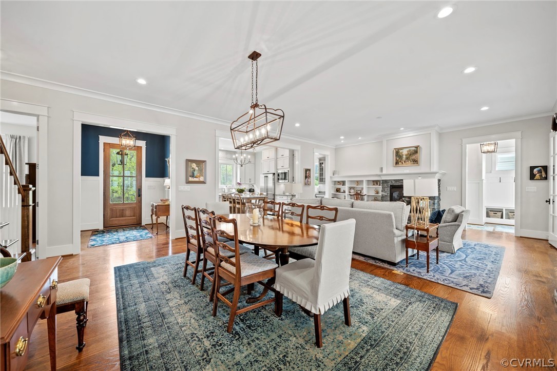 Dining room with ornamental molding, light hardwood / wood-style floors, and an inviting chandelier