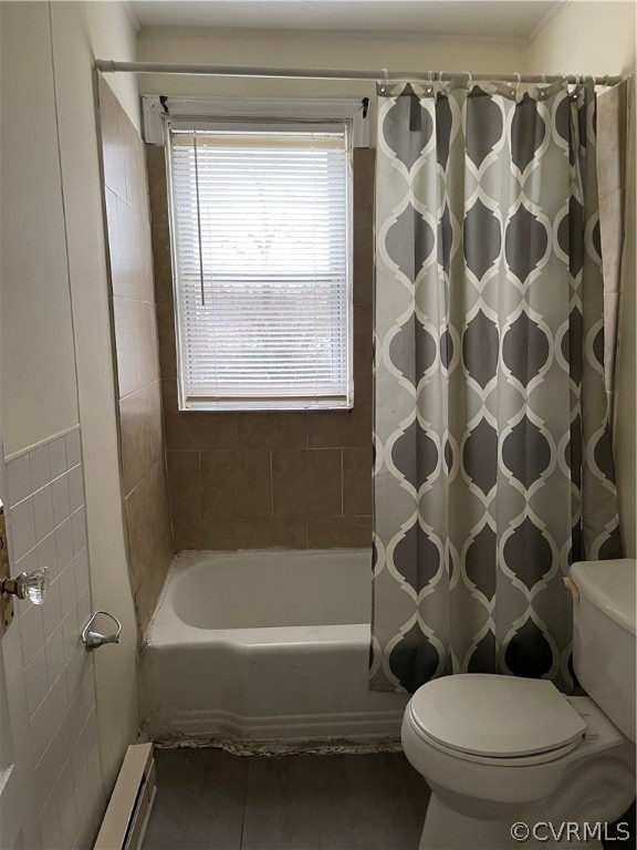Bathroom with a baseboard radiator, shower / tub combo with curtain, and toilet