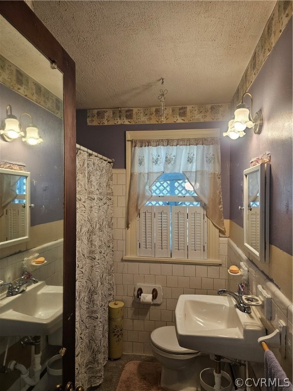 Bathroom with backsplash, toilet, tile walls, and a textured ceiling