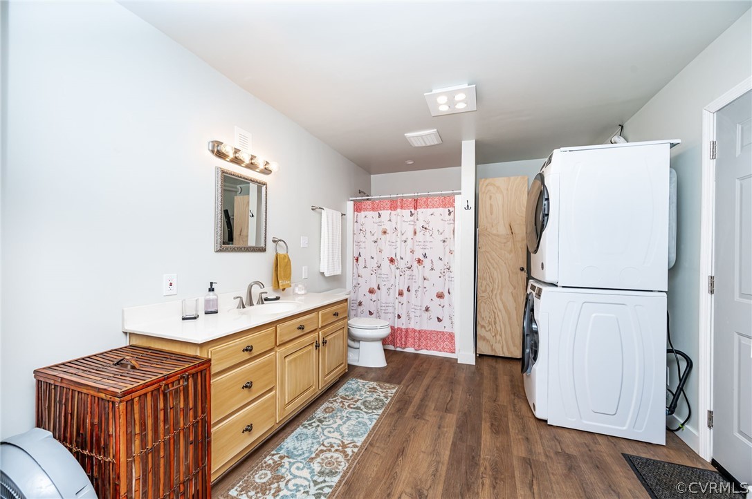 Bathroom featuring stacked washing maching and dryer, toilet, vanity, and wood-type​​‌​​​​‌​​‌‌​‌‌​​​‌‌​‌​‌​‌​​​‌​​ flooring