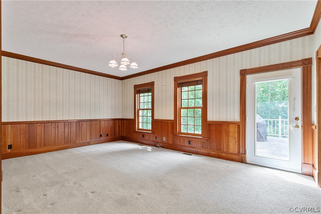 Living area with a textured ceiling, a wealth of natural light, light hardwood floors, and ornamental molding