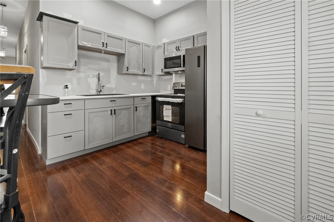 Kitchen featuring gray cabinetry, stainless steel appliances, dark hardwood / wood-style floors, and sink