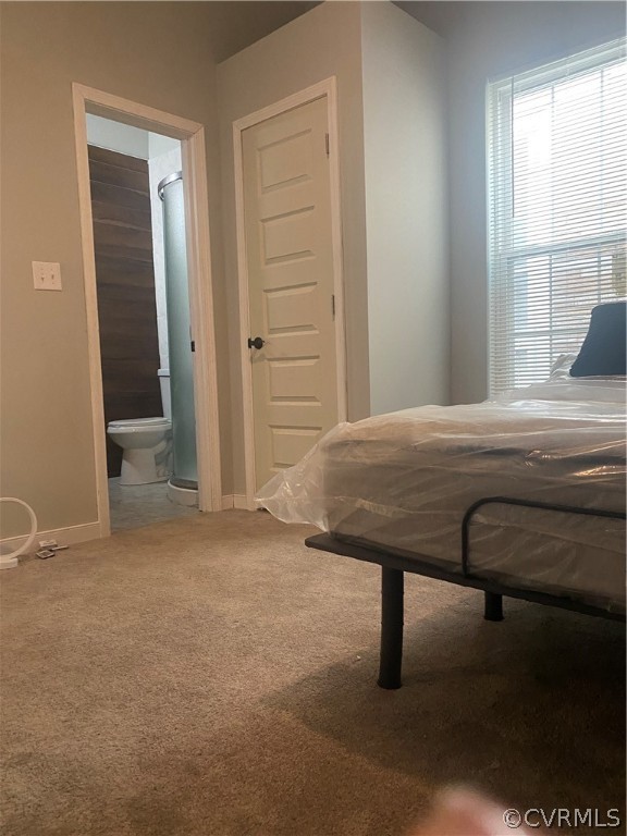 Bedroom featuring a closet, connected bathroom, and carpet flooring