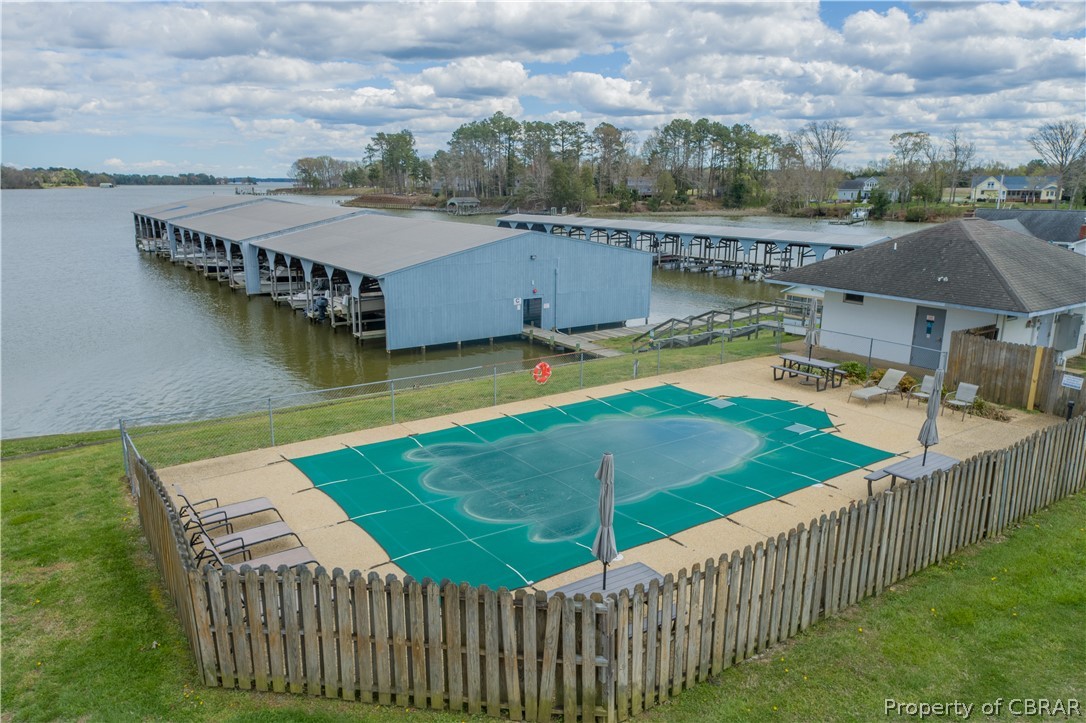 View of pool with a dock, a patio area, a lawn, and a water view