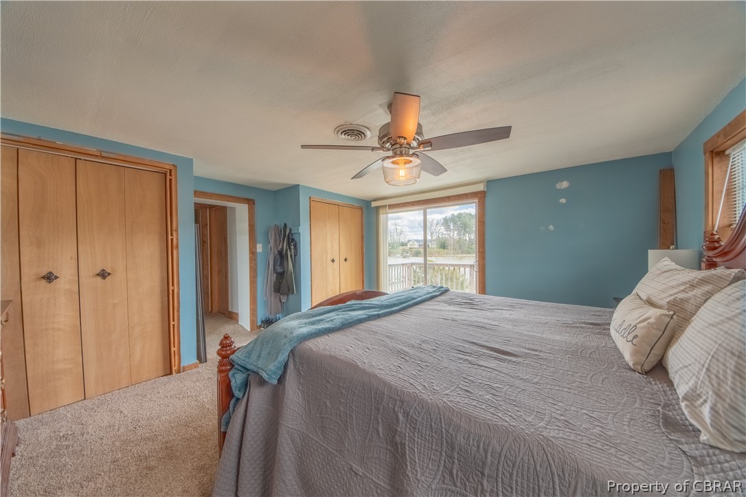 Bedroom featuring light carpet, ceiling fan, and multiple closets