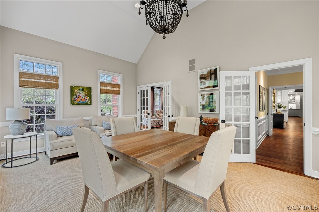 Dining room with light hardwood / wood-style flooring, french doors, a chandelier, and a high ceiling
