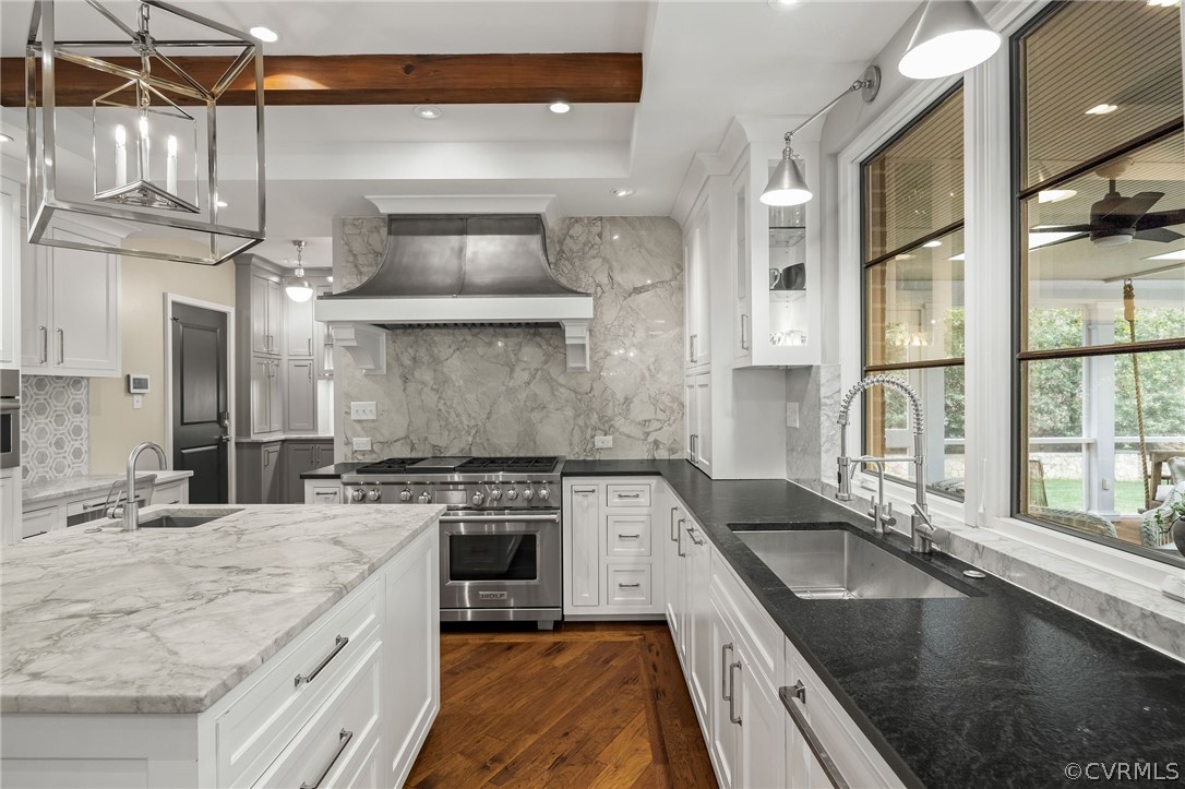 Kitchen with premium range hood, hanging light fixtures, backsplash, appliances with stainless steel finishes, and sink