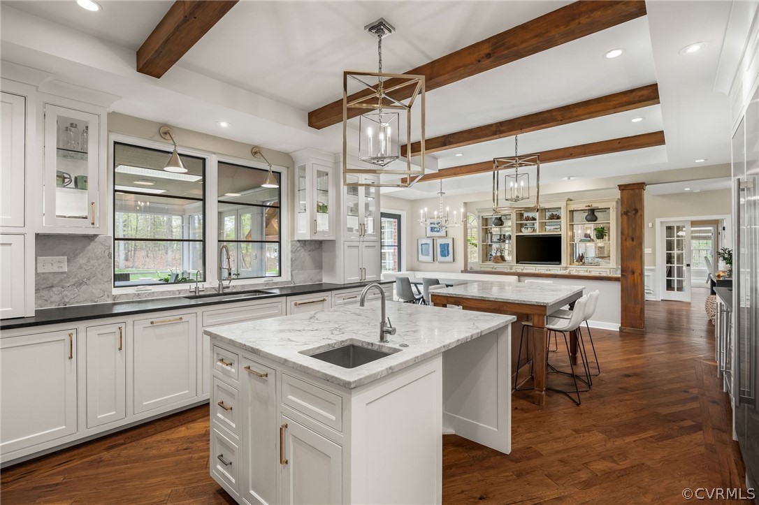 Kitchen featuring hanging light fixtures, tasteful backsplash, sink, and an island with sink