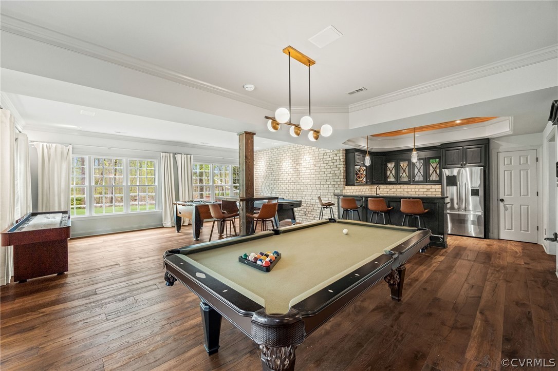 Playroom with hardwood / wood-style floors, a tray ceiling, ornamental molding, bar, and billiards