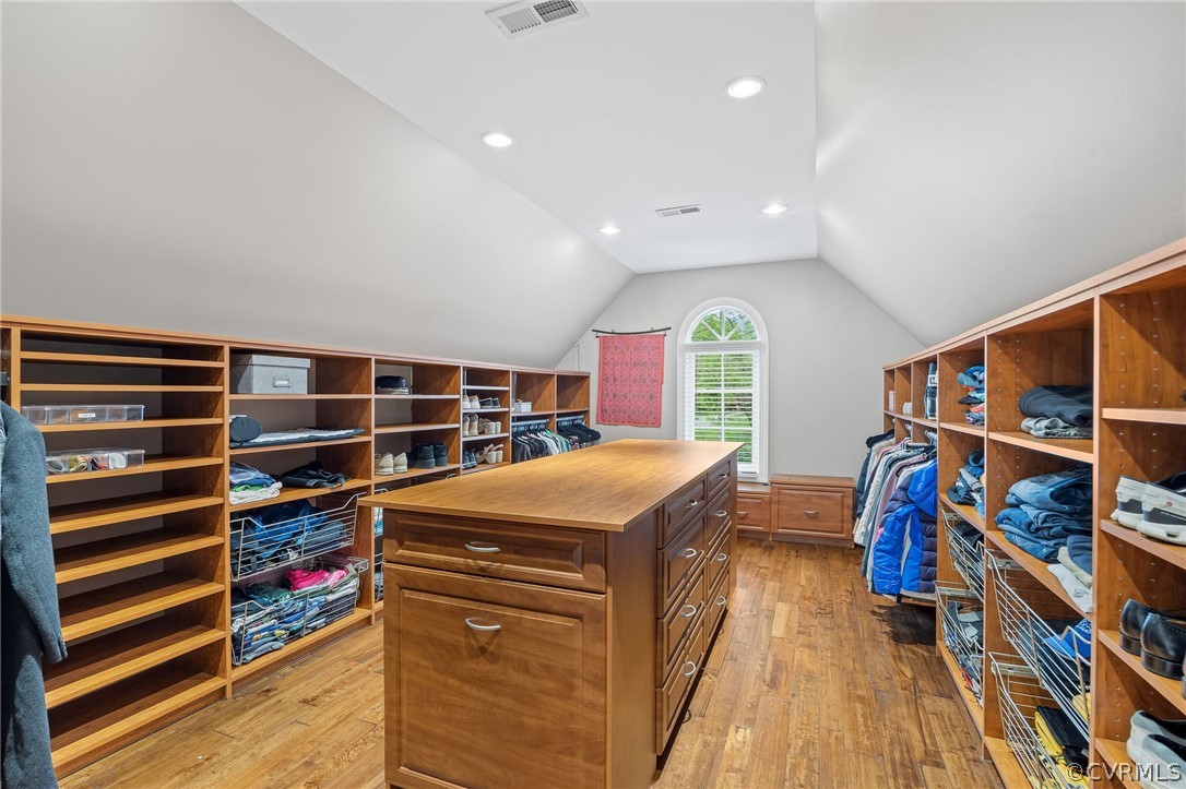 Walk in closet with vaulted ceiling and light hardwood / wood-style floors
