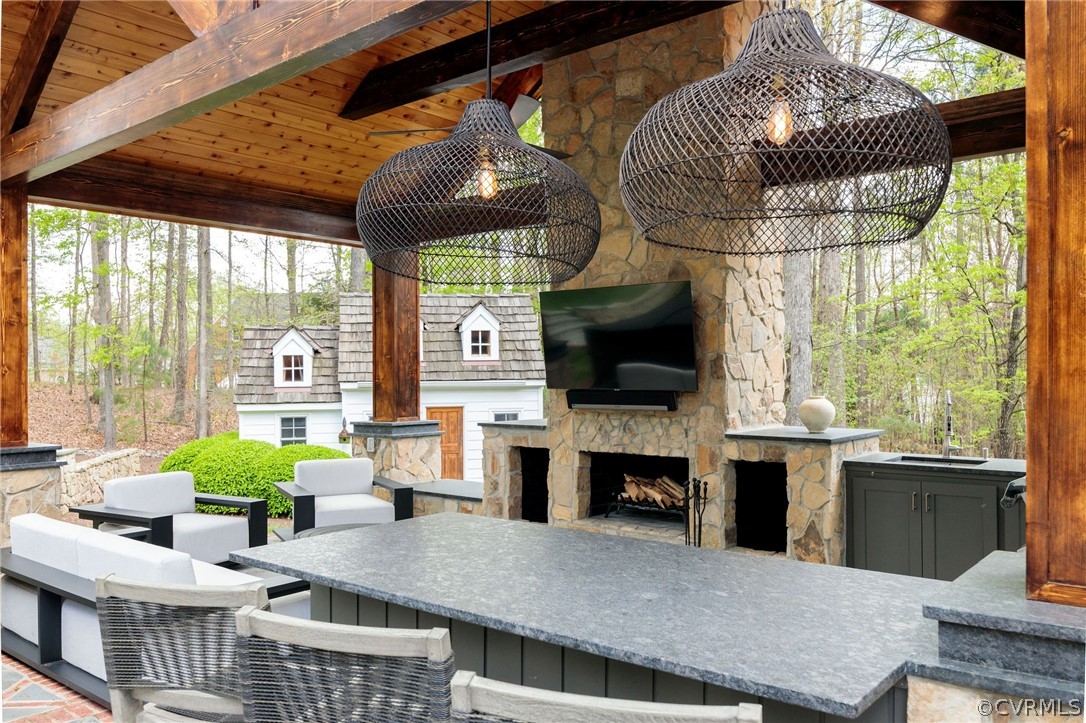 View of terrace with an outdoor stone fireplace and ceiling fan