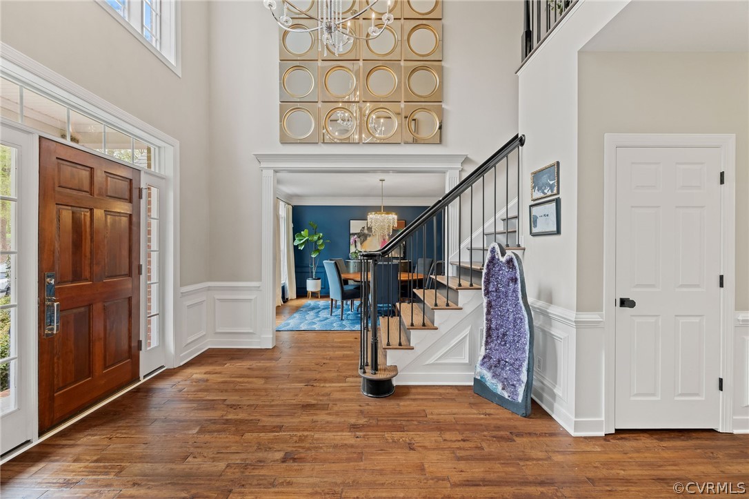 Foyer with plenty of natural light, a towering ceiling, dark hardwood / wood-style floors, and an inviting chandelier