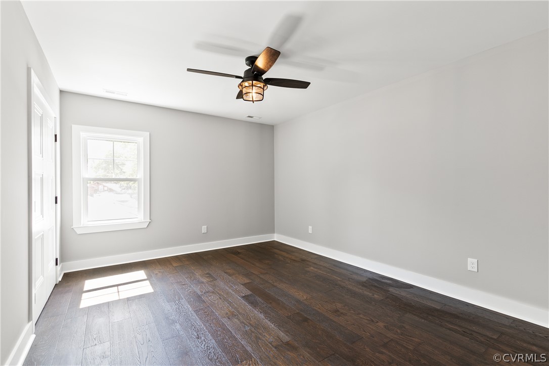 Unfurnished room with ceiling fan and dark wood-type flooring