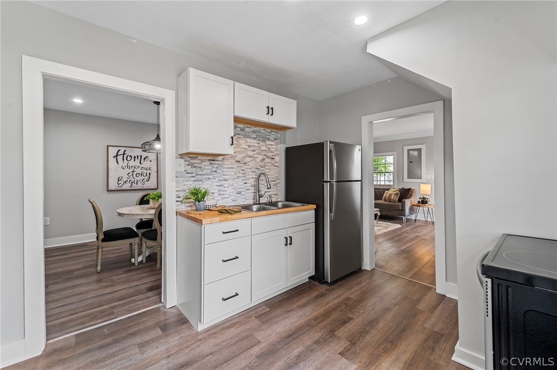 Kitchen featuring white cabinets, stainless steel refrigerator, dark hardwood / wood-style floors, backsplash, and electric range