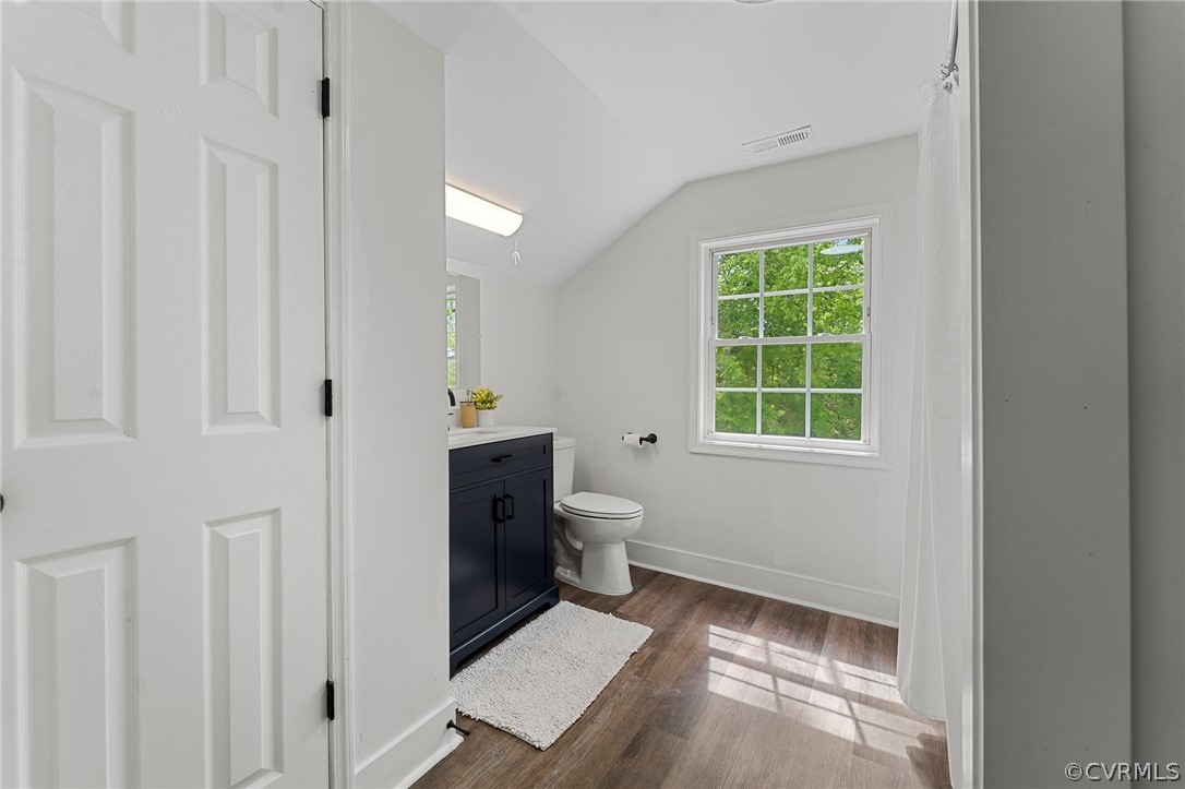 Bathroom featuring lofted ceiling, hardwood / wood-style floors, vanity, and toilet