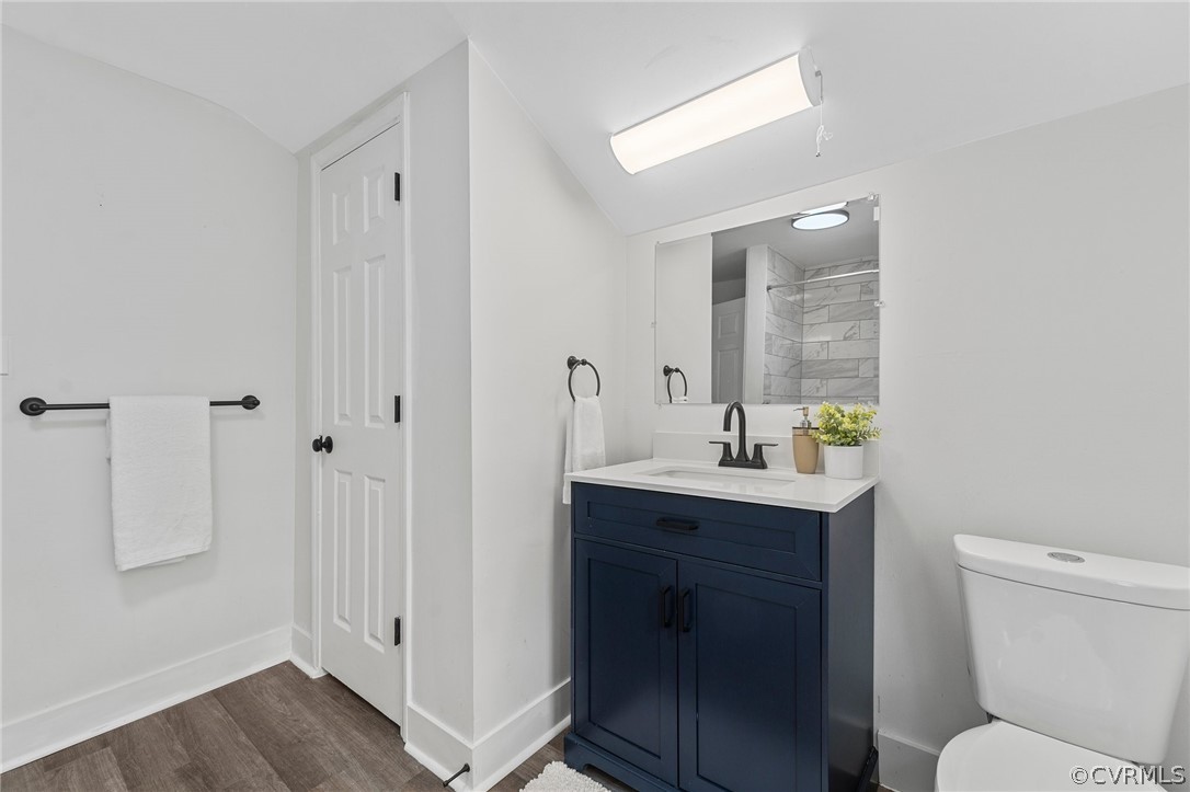 Bathroom featuring hardwood / wood-style flooring, toilet, vanity, and lofted ceiling