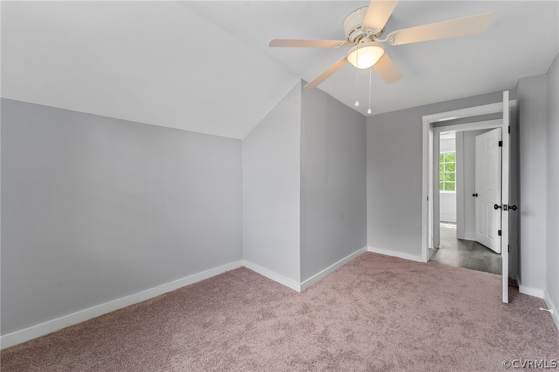 Spare room featuring lofted ceiling, ceiling fan, and light carpet