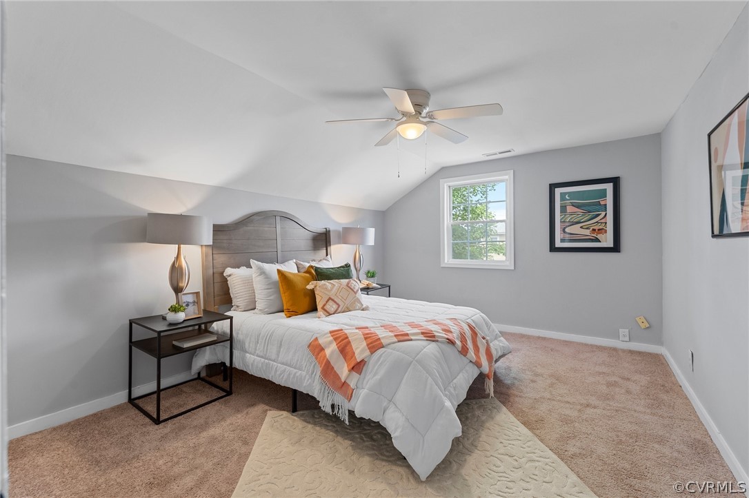 Bedroom with ceiling fan, vaulted ceiling, and light carpet