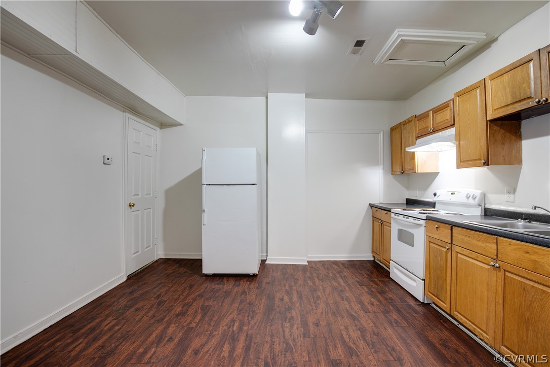 Kitchen featuring dark hardwood / wood-style flooring, white appliances, and sink