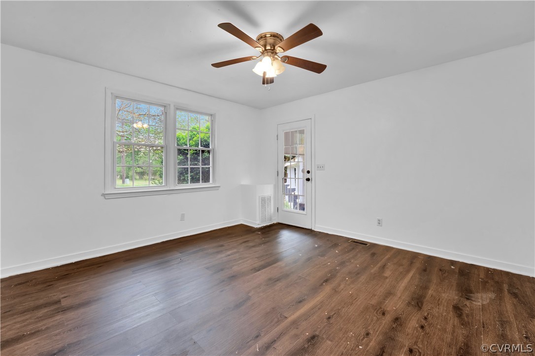 Empty room with ceiling fan and dark hardwood / wood-style flooring