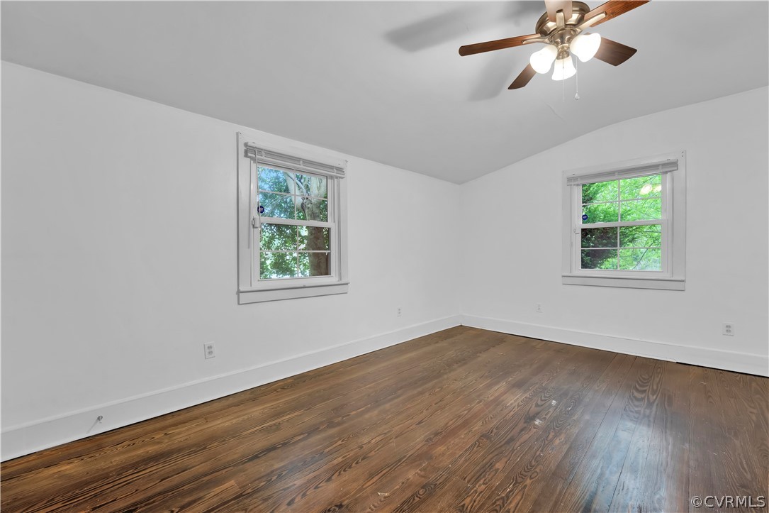 Empty room featuring vaulted ceiling, ceiling fan, and dark hardwood / wood-style flooring