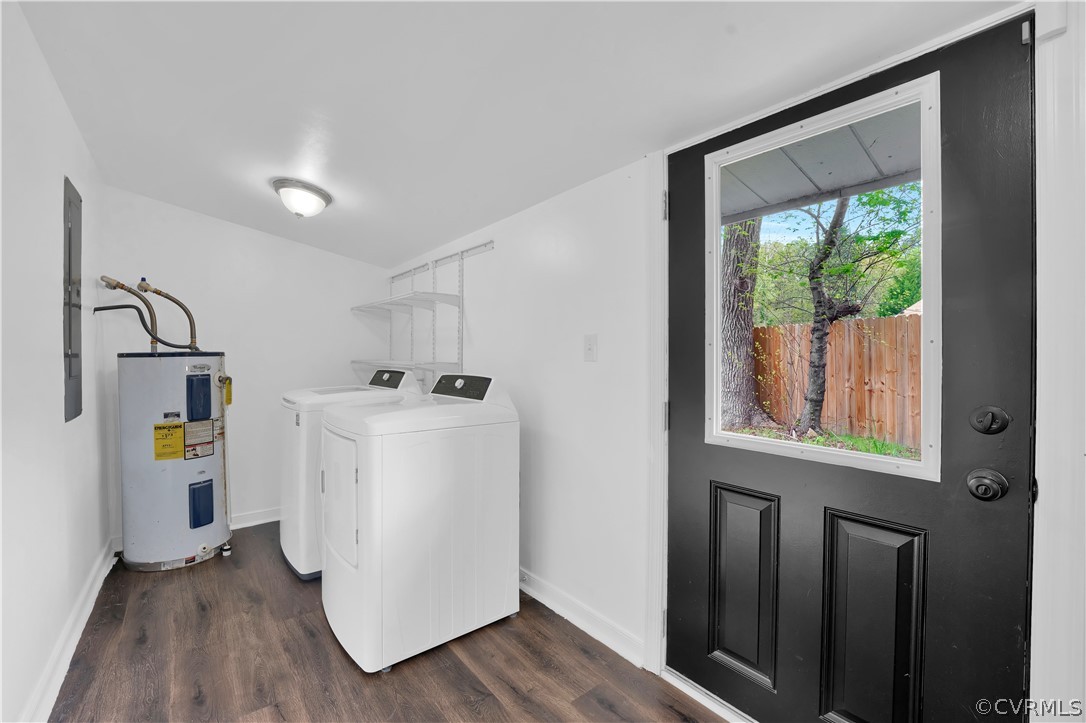 Clothes washing area featuring washer and clothes dryer, dark hardwood / wood-style flooring, and electric water heater
