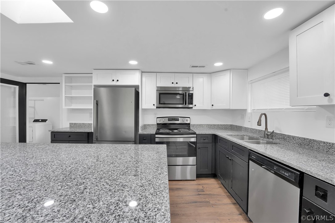 Kitchen featuring appliances with stainless steel finishes, light hardwood / wood-style flooring, and white cabinets