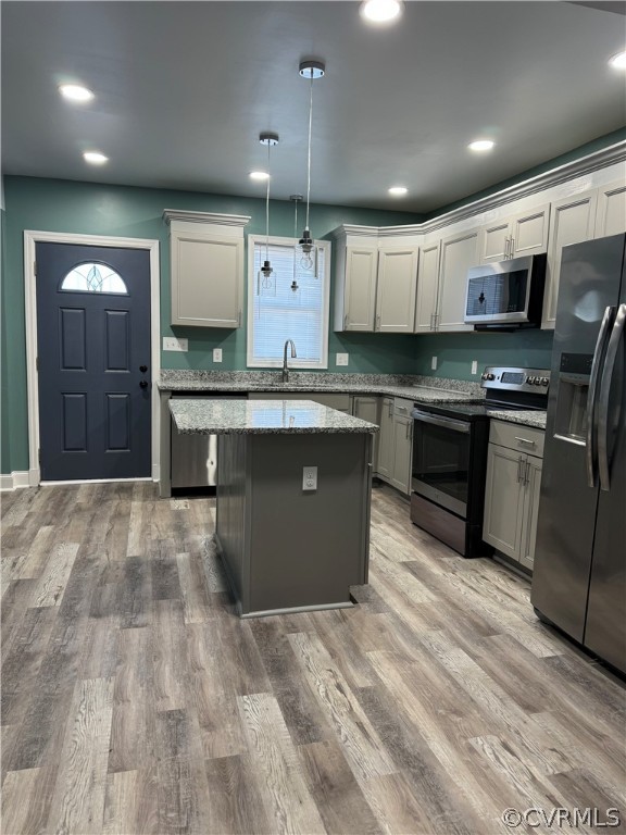 Kitchen with light stone counters, range with electric cooktop, light wood-type flooring, black fridge with ice dispenser, and hanging light fixtures