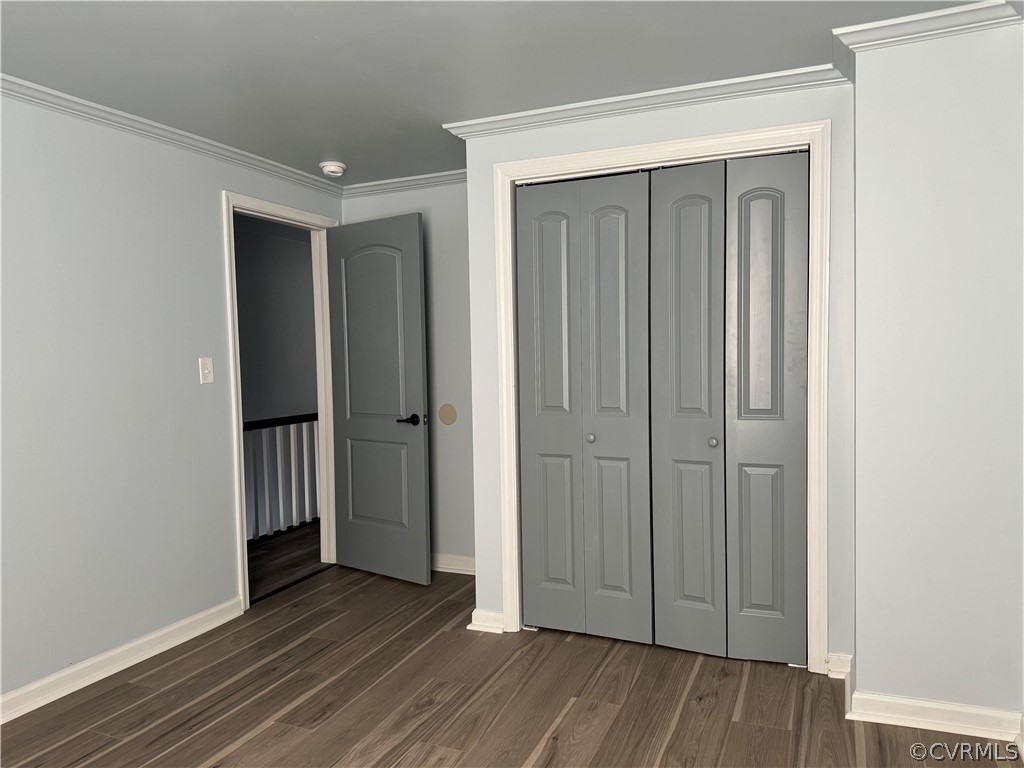 Unfurnished bedroom featuring crown molding, a closet, and dark hardwood / wood-style floors