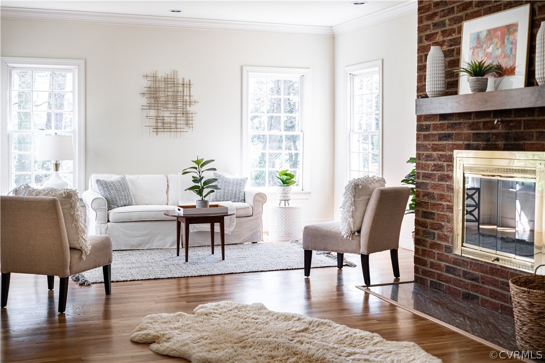Living area featuring dark hardwood / wood-flooring, a brick fireplace, and crown molding