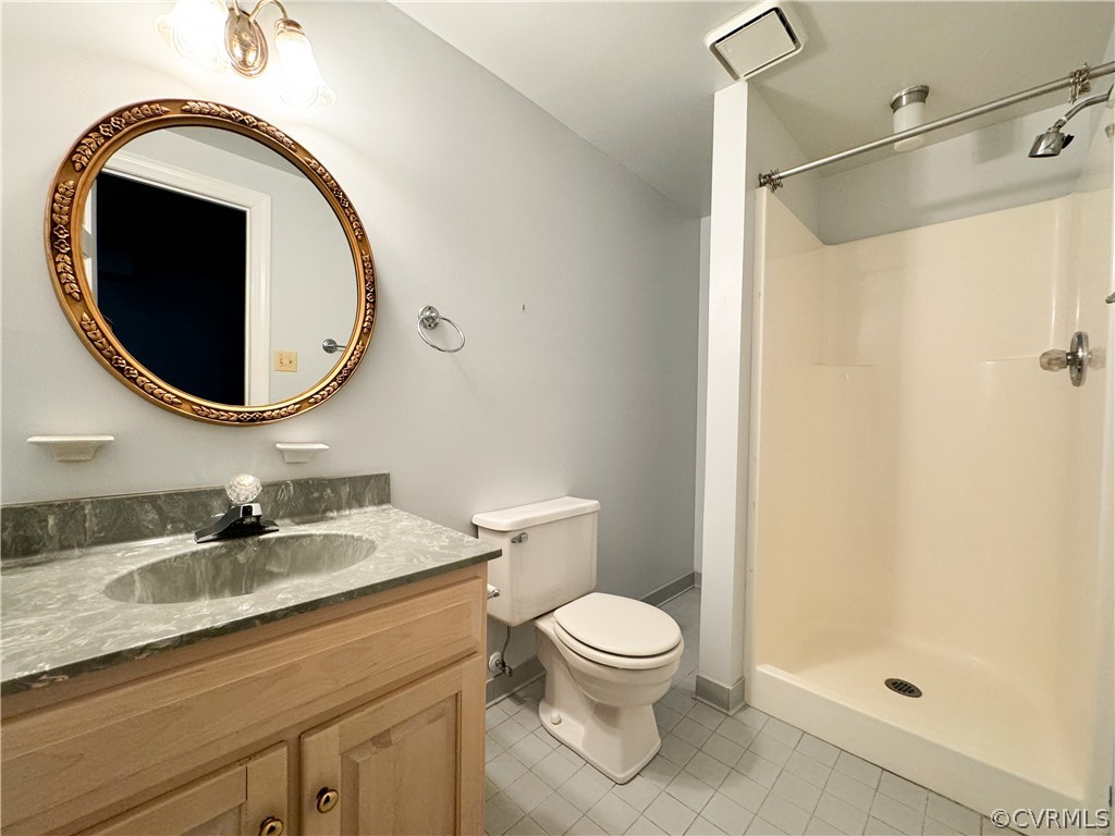 Basement Bathroom with walk in shower, vanity, toilet, and tile flooring