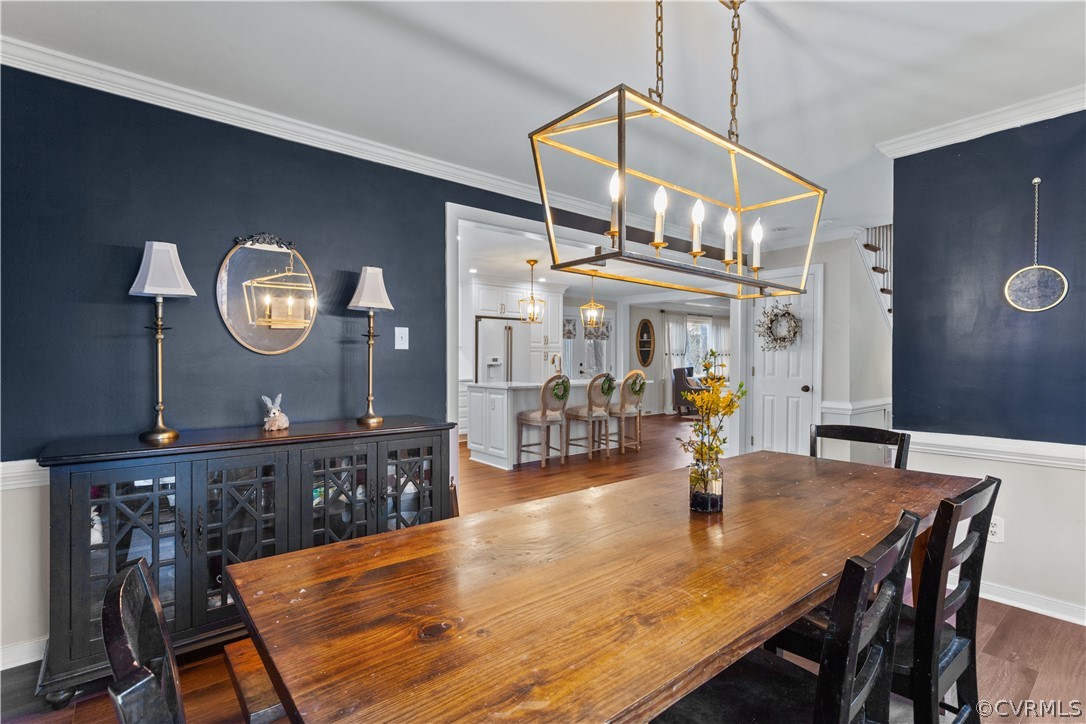 Dining space featuring dark hardwood / wood-style flooring, crown molding, and an inviting chandelier