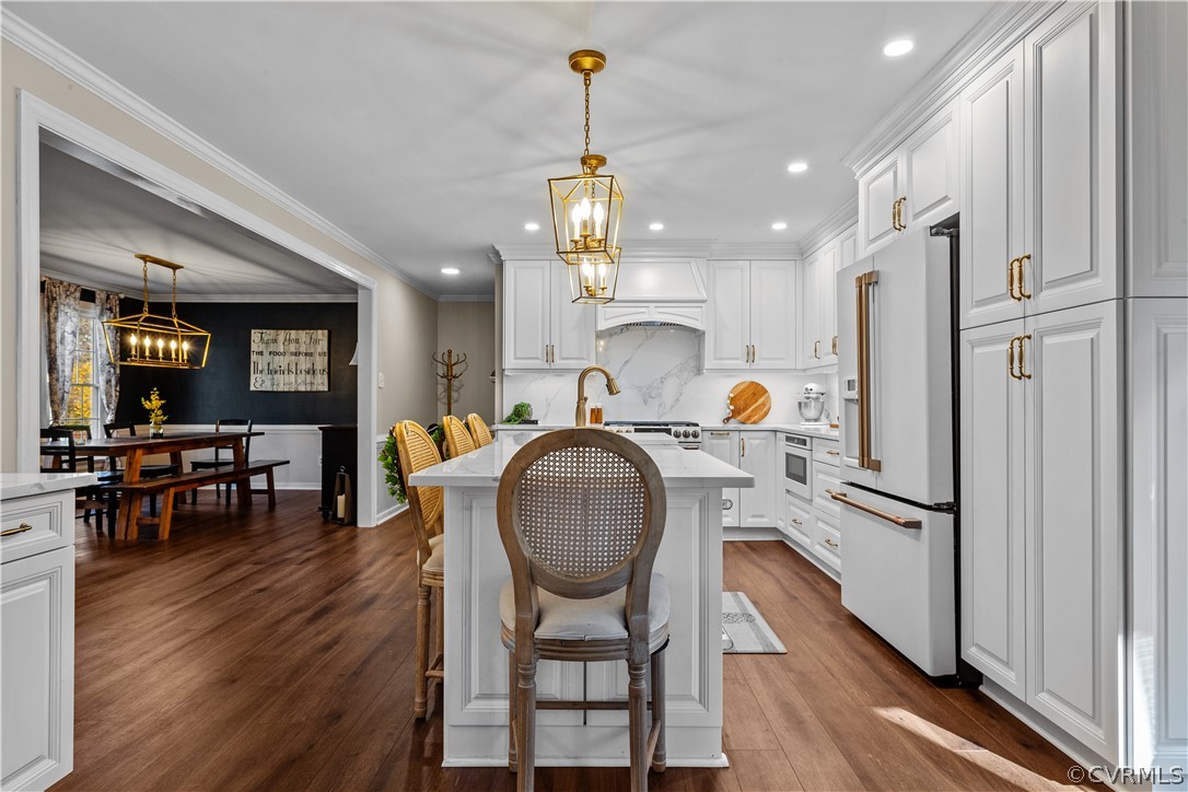 Kitchen with high end white fridge, pendant lighting, dark wood-type flooring, and white cabinets