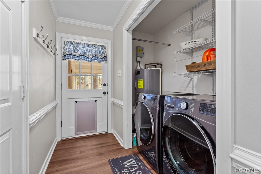 Washroom with dark hardwood / wood-style flooring, crown molding, electric water heater, and washing machine and clothes dryer