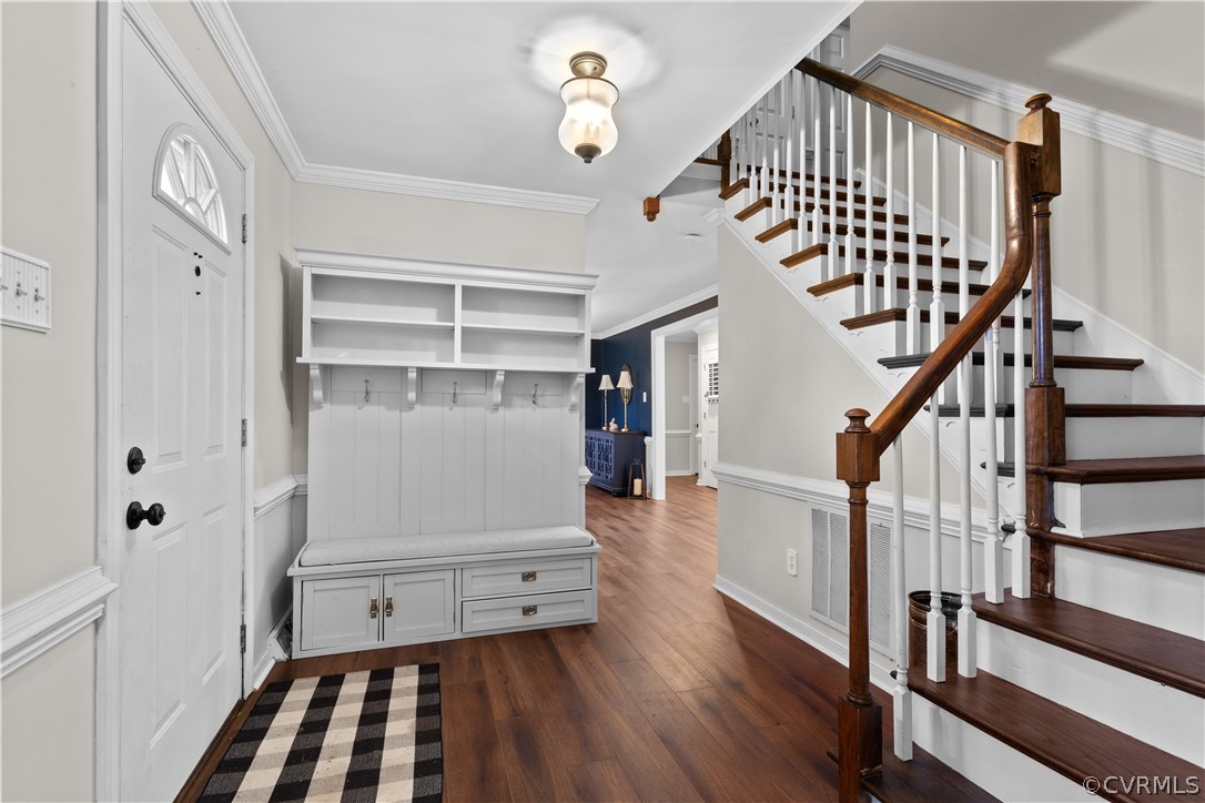 Entryway with crown molding and dark wood-type flooring