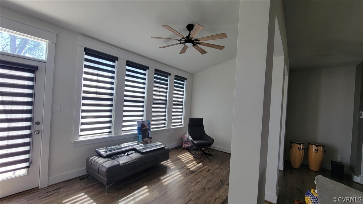 Living area with ceiling fan and dark wood-type flooring