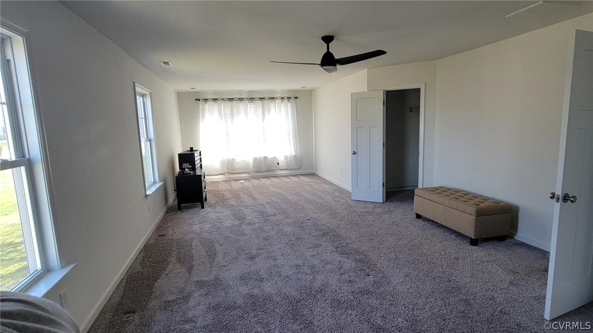Unfurnished bedroom featuring carpet floors, multiple windows, and ceiling fan