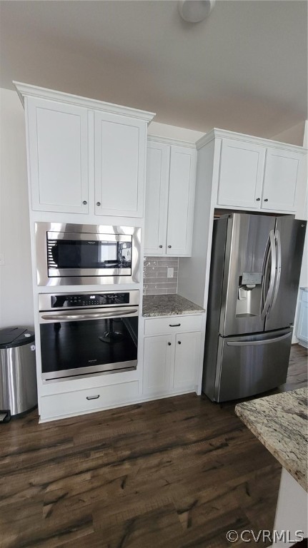 Kitchen featuring tasteful backsplash, dark hardwood / wood-style floors, refrigerator, white cabinets, and oven