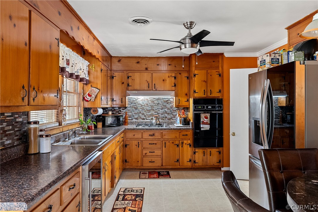 Kitchen with beverage cooler, ceiling fan, sink, light tile flooring, and backsplash