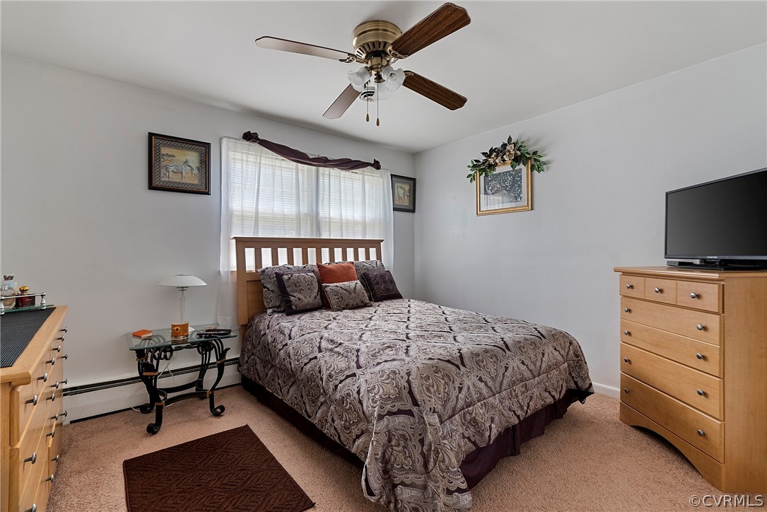 Carpeted bedroom featuring ceiling fan and baseboard heating