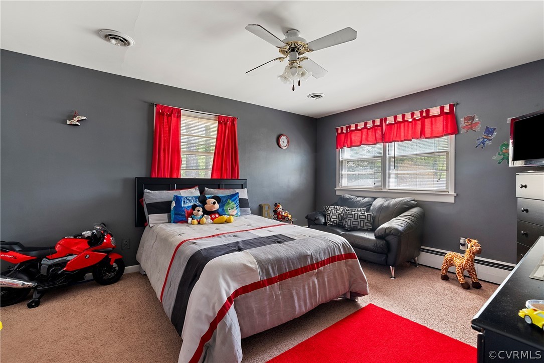 Bedroom featuring ceiling fan, carpet, and a baseboard heating unit