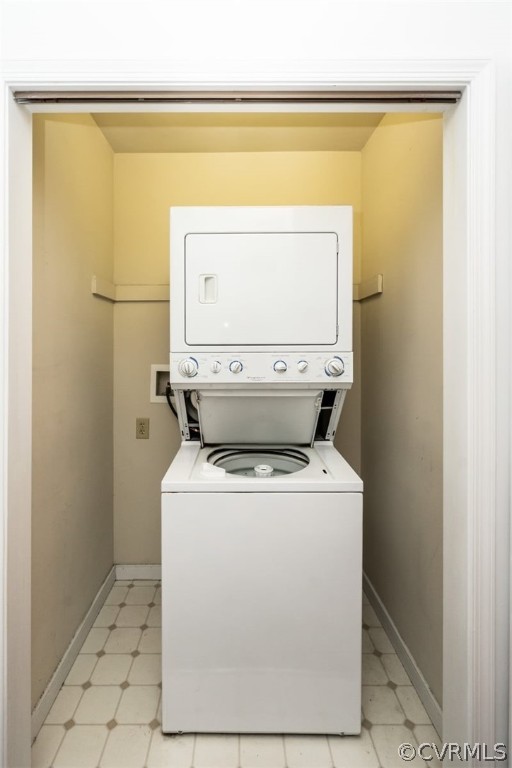 Washroom with light tile floors and stacked washer / drying machine