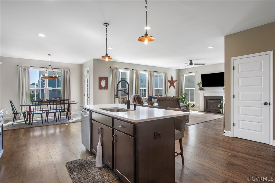 Kitchen featuring hanging light fixtures, dark brown cabinets, a wealth of natural light, and dark wood-type flooring