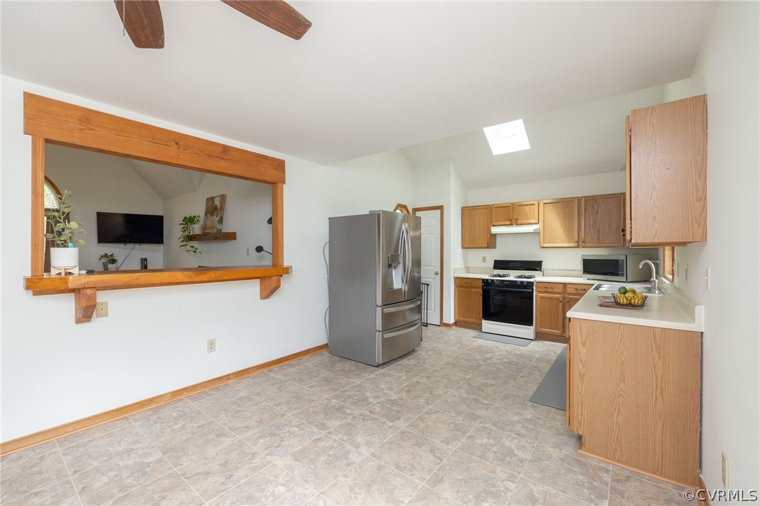 Kitchen featuring stainless steel fridge with ice dispenser, ceiling fan, light tile floors, and range with gas stovetop